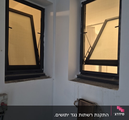 שני חלונות אלומיניום פתוחים בקיר לבן